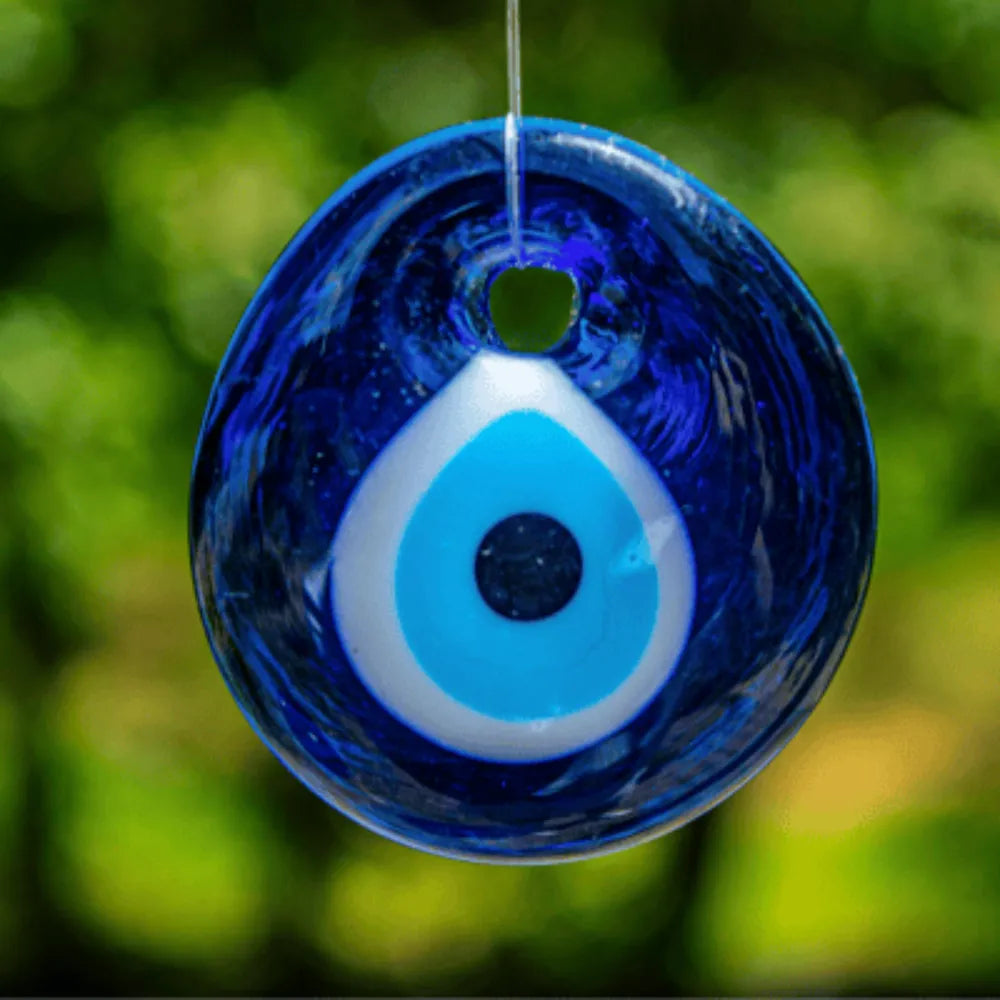 Blue evil eye talisman hanging in a window — protection symbol jewelry guide
