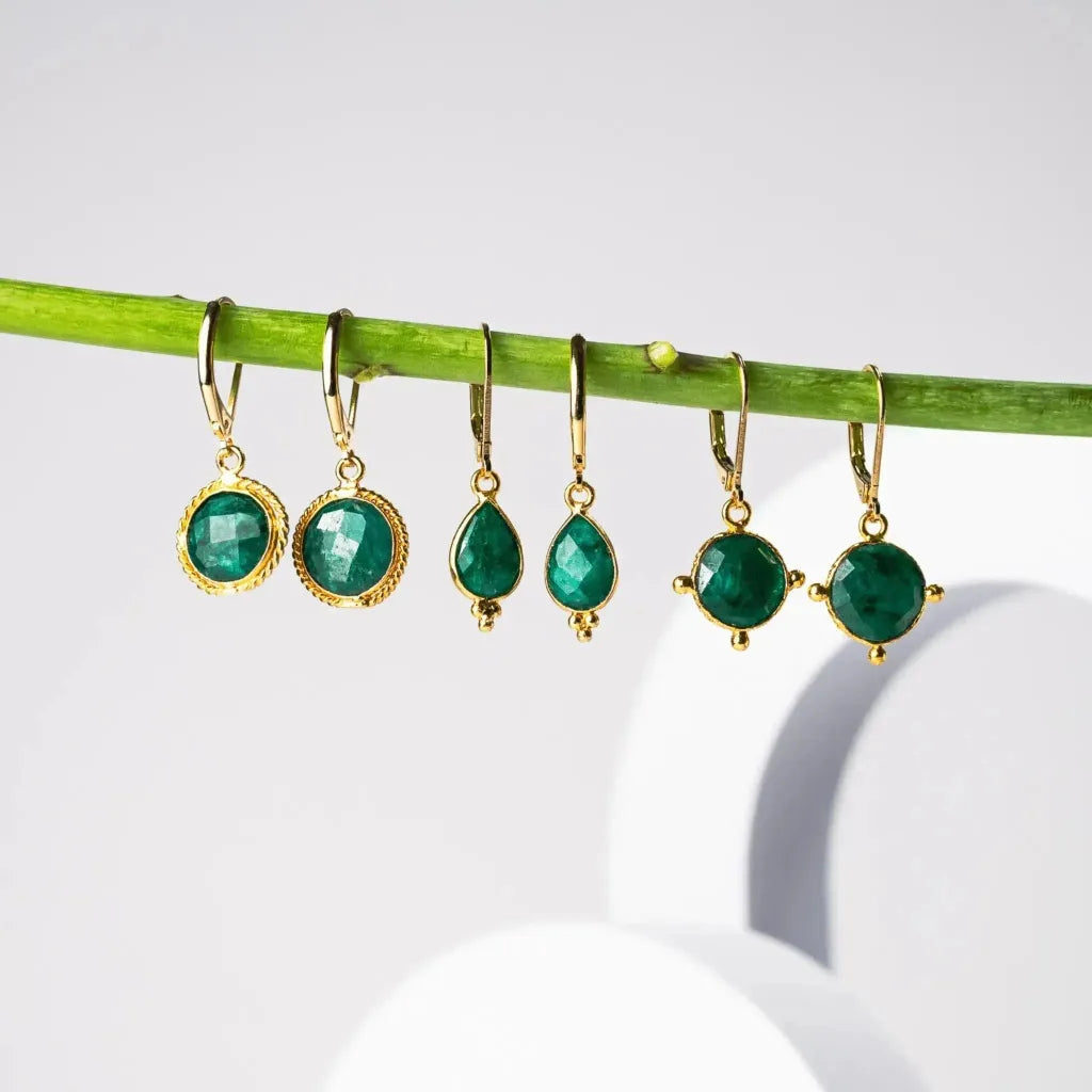 Emerald green drop earrings hanging from a branch — May birthstone jewelry