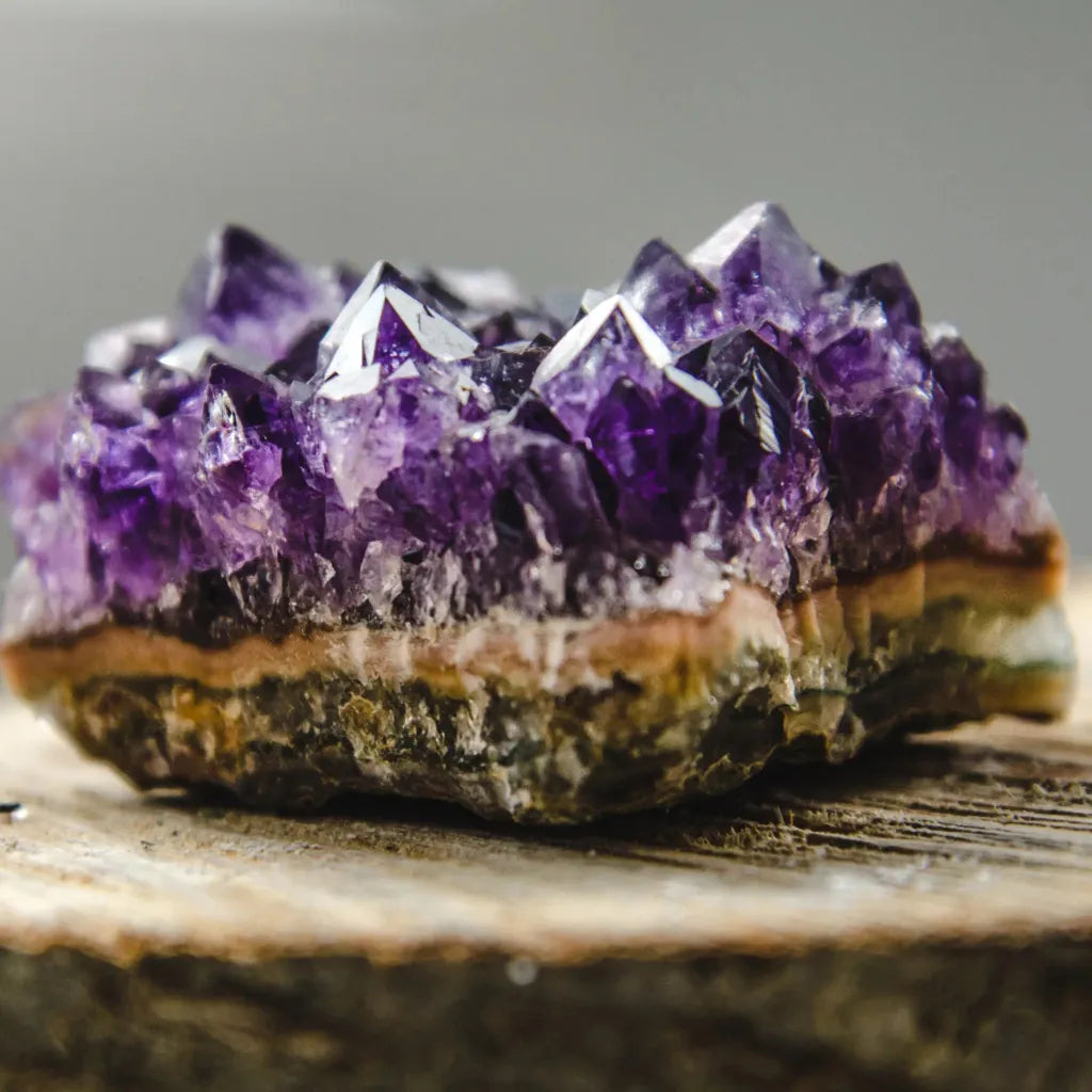 Natural amethyst crystal on a wood table — February birthstone jewelry