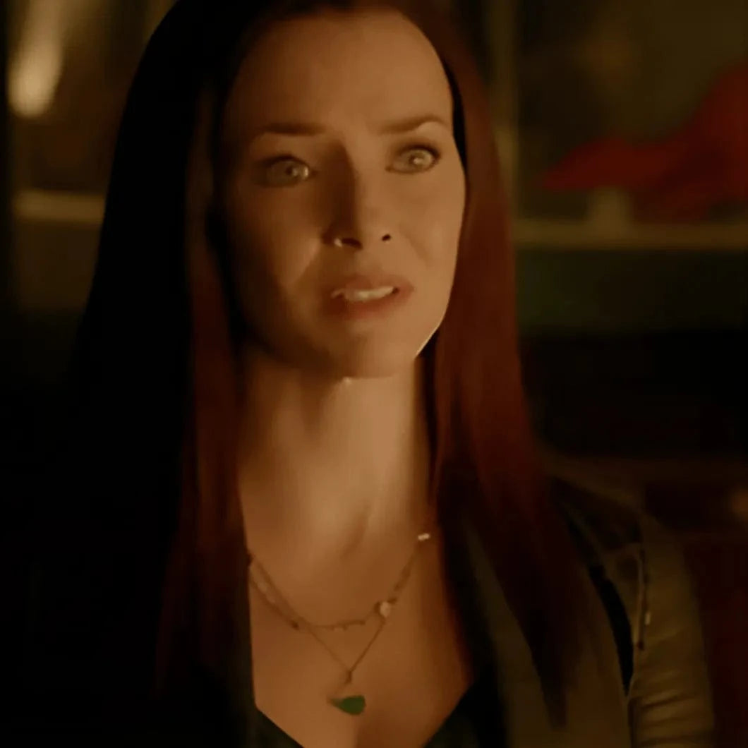 Woman with red hair wearing a necklace in a dimly lit room