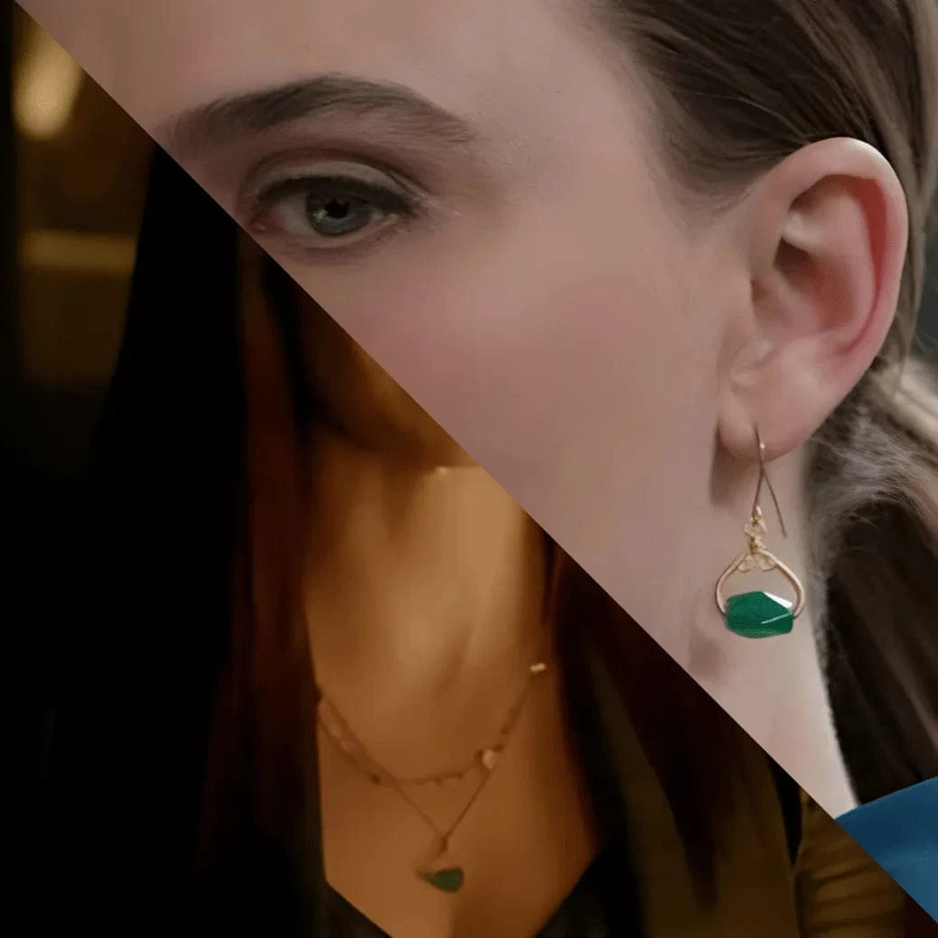 Close-up of a person wearing a gold earring with a green gemstone.