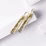 Gold earrings with intricate design on a light gray background