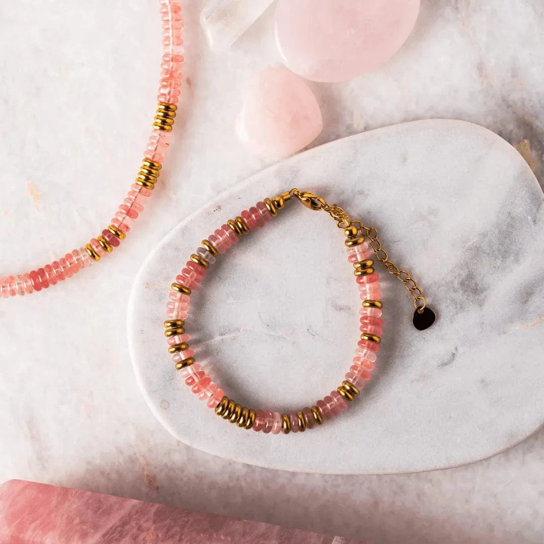 Pink beaded bracelet with gold accents on a marble surface
