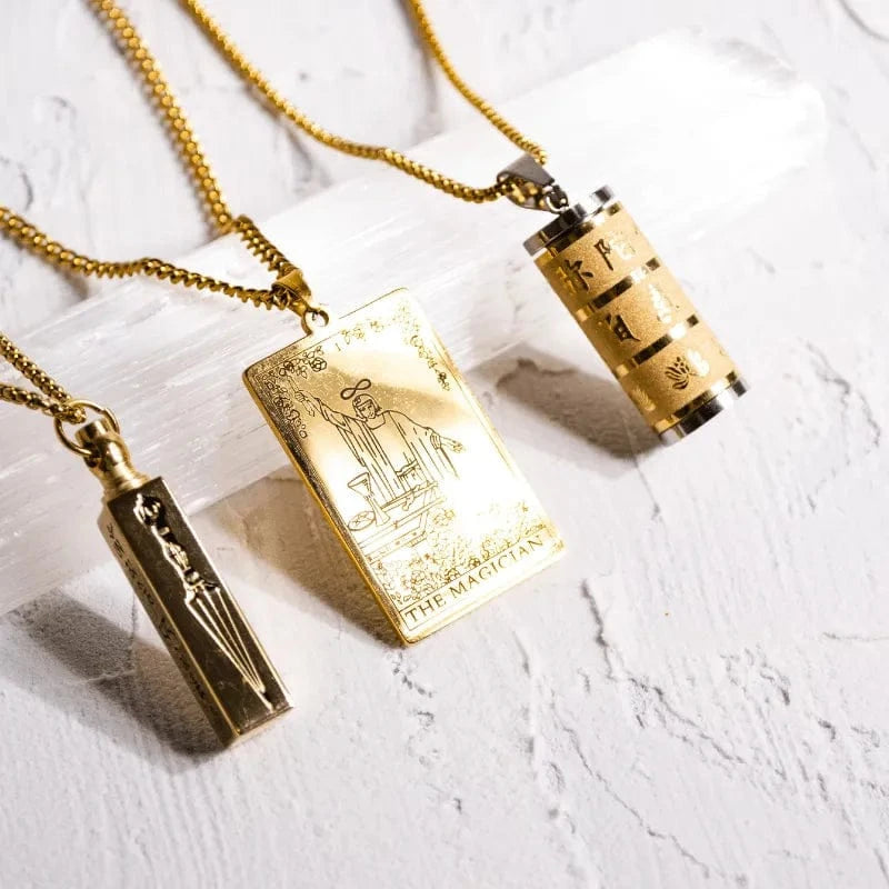 Three gold necklaces with different pendants on a light gray surface