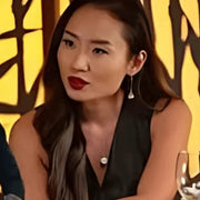 Woman with red lipstick and dark hair against a warm-toned background
