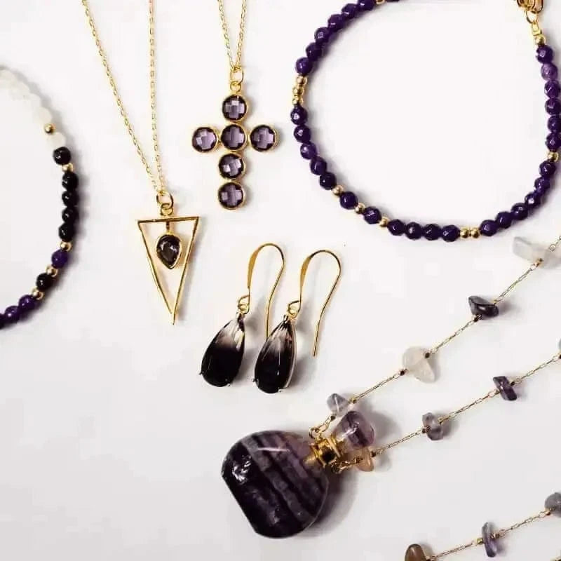 Amethyst jewelry collection featuring a triangle pendant, earrings, and various necklaces in gold and purple tones.