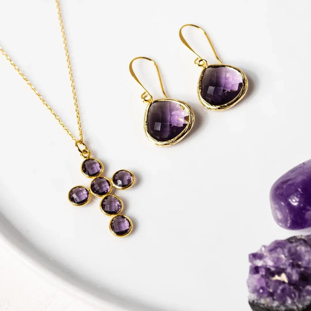 Amethyst jewelry set with necklace and earrings on a white surface with amethyst stones.