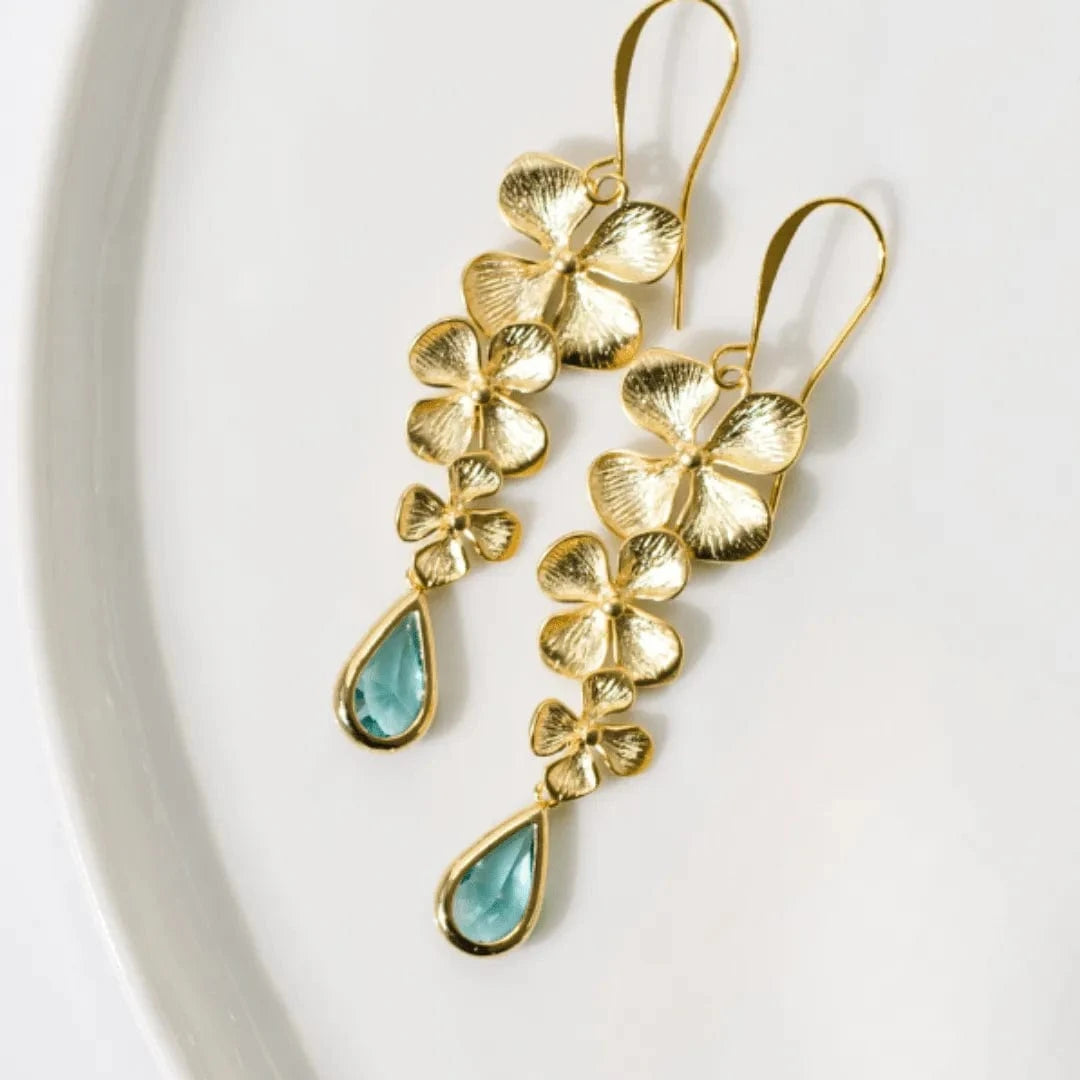Gold floral earrings with turquoise drops on a white background