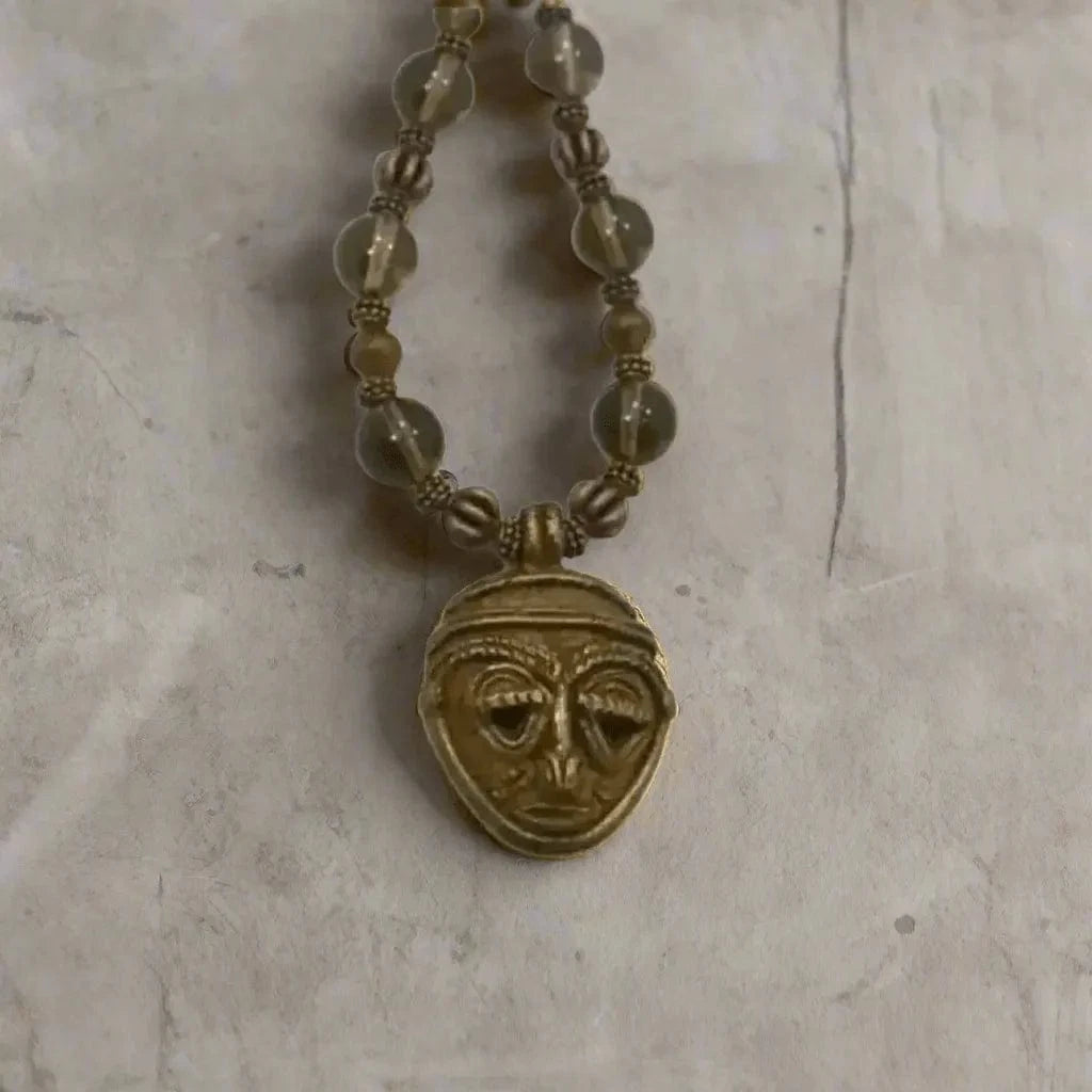 Necklace with a face-shaped pendant on a textured surface