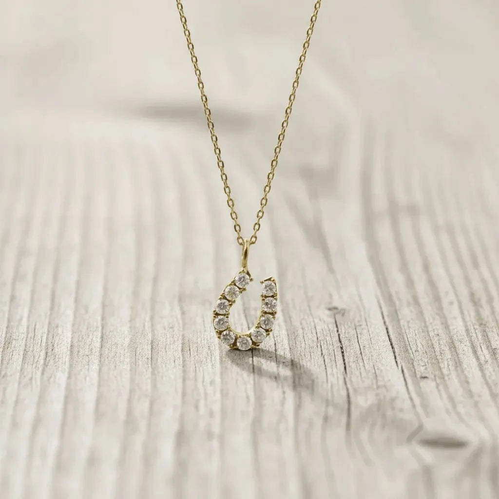 Gold necklace with a teardrop-shaped pendant on a wooden surface