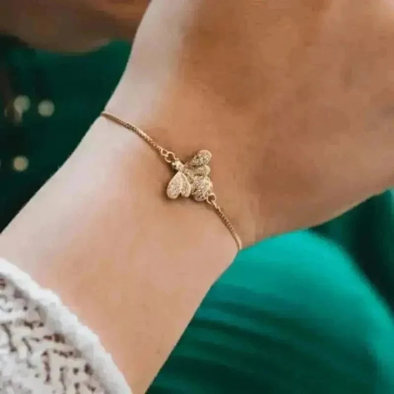 Gold butterfly bracelet on a wrist with a blurred background