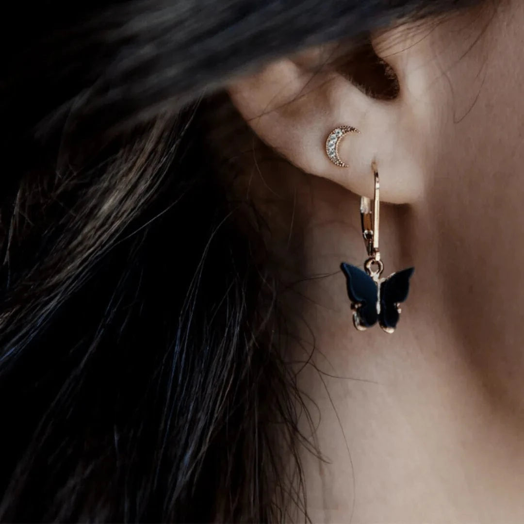 Close-up of an ear wearing a butterfly earring with a blurred background