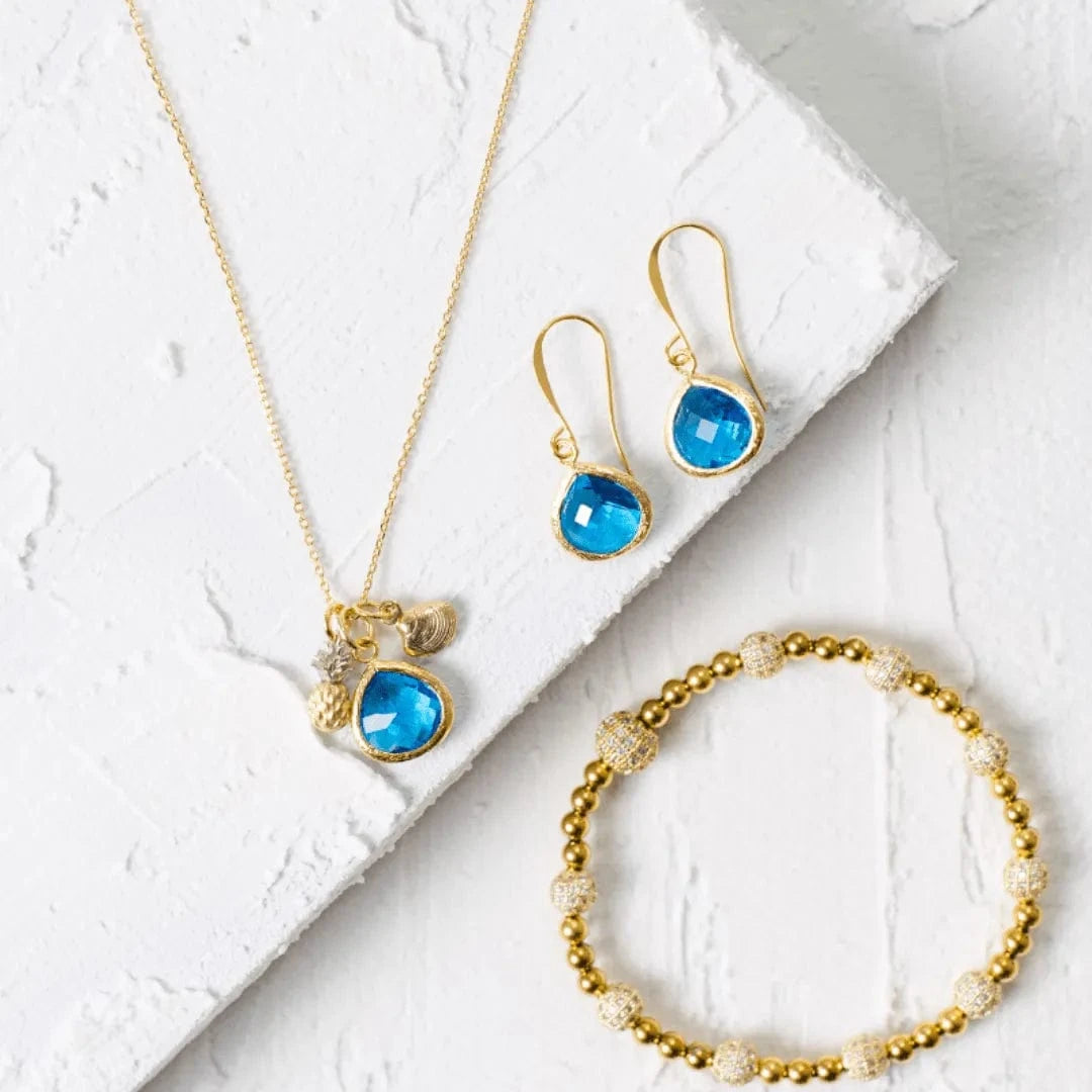 Jewelry set with necklace, earrings, and bracelet featuring blue gemstones on a white background