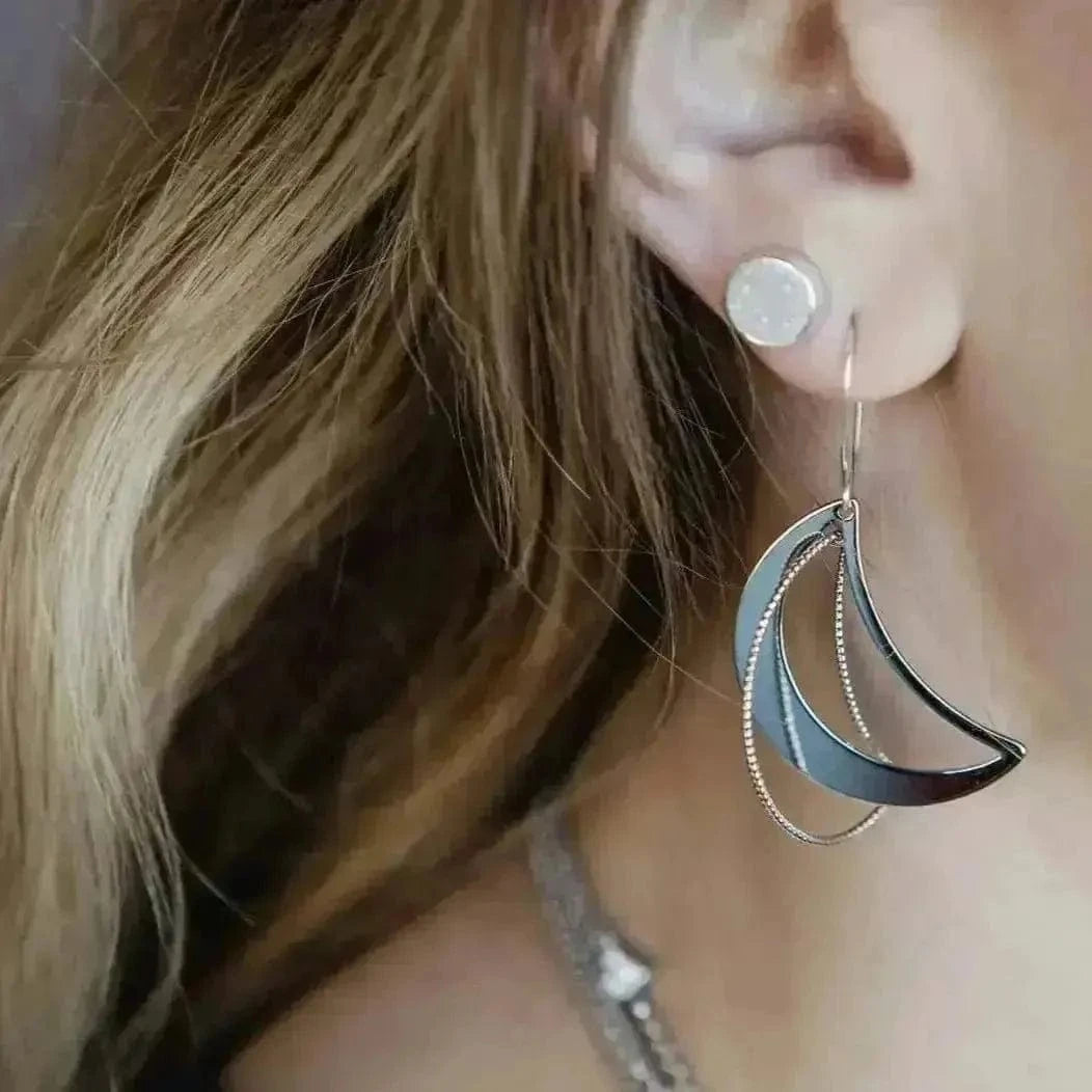 Close-up of a person wearing a unique earring with layered crescent shapes.