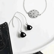 Silver jewelry set with black gemstones on a white surface