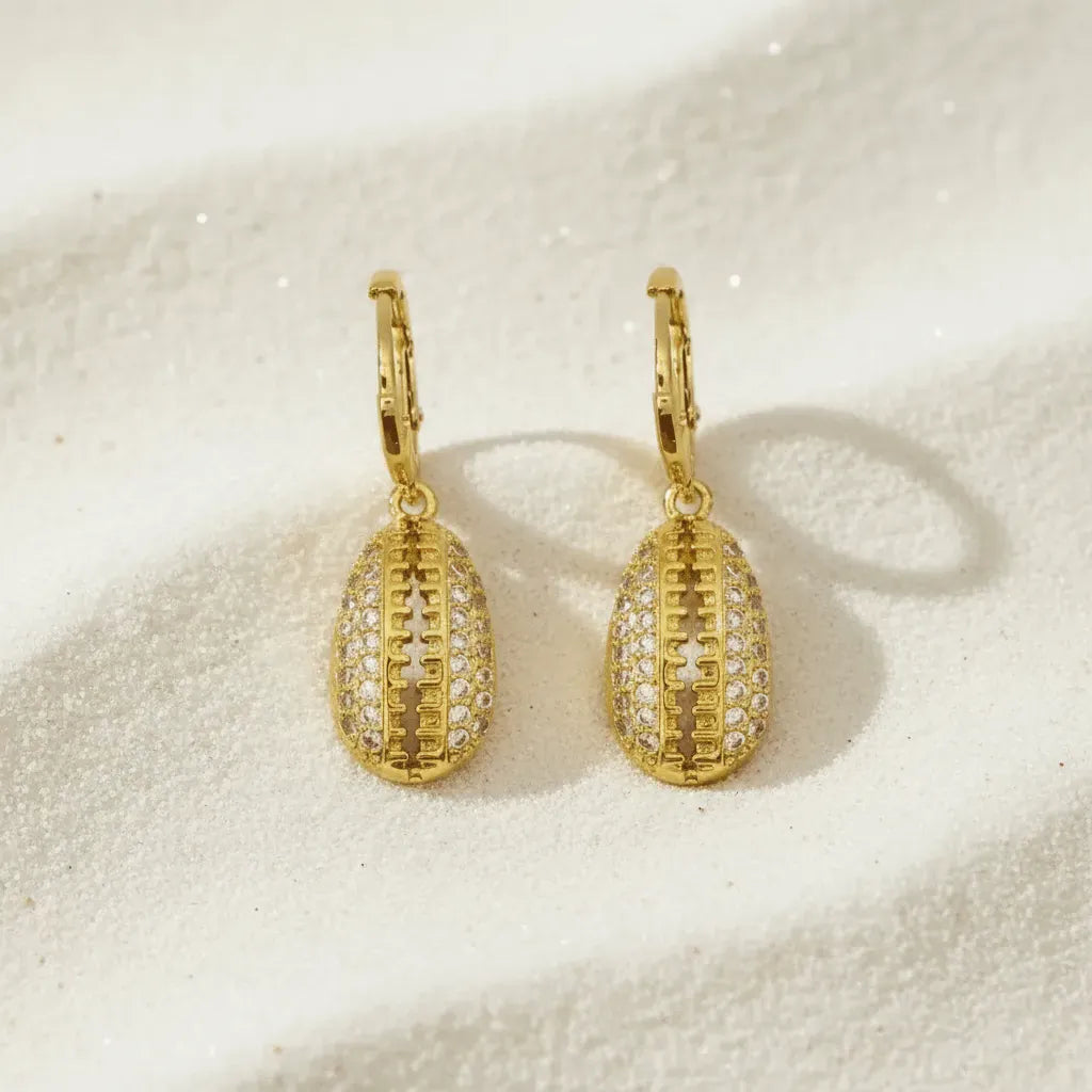 Gold earrings with intricate designs on a beige surface