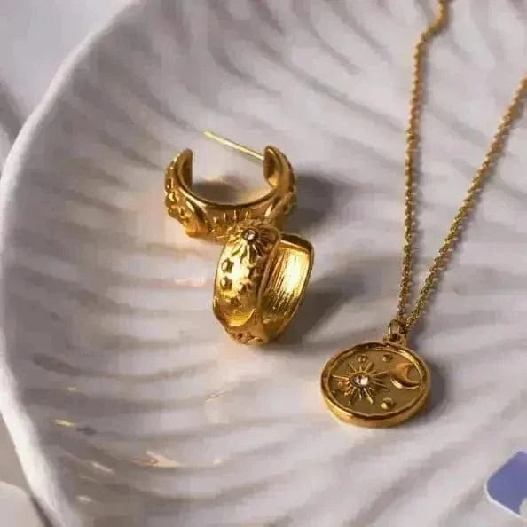 Gold hoop earrings and necklace on a textured white surface