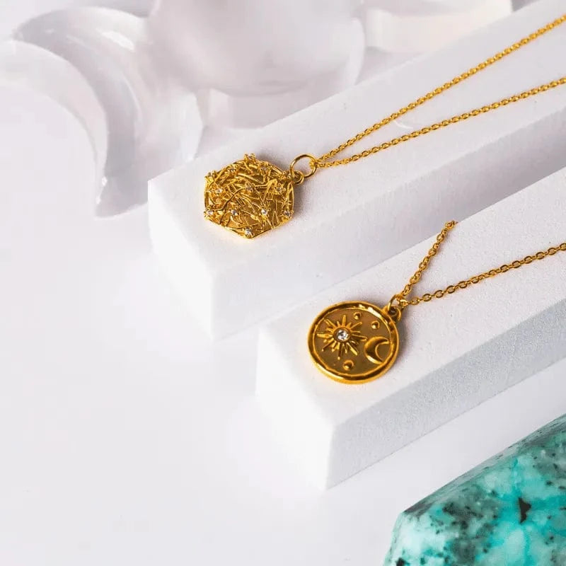 Gold necklaces with intricate pendants on a white surface