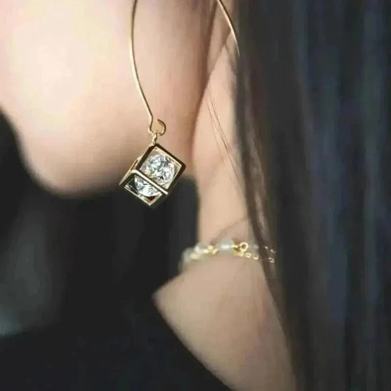 Gold earring with a diamond-like stone worn by a person.