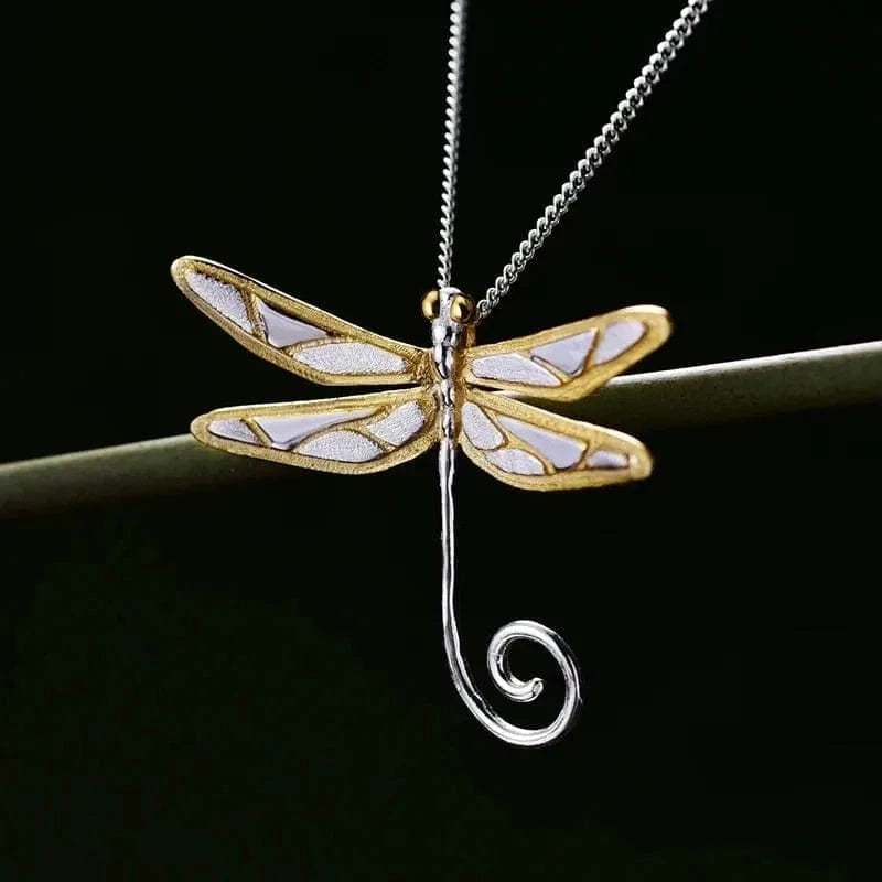 Dragonfly-shaped pendant on a chain against a dark background