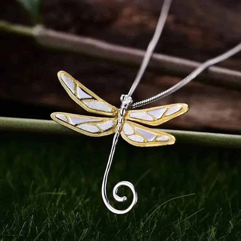Dragonfly-shaped pendant on a chain against a natural background