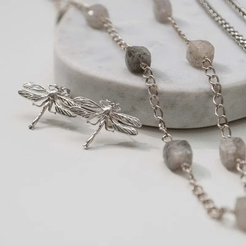 Silver necklace with dragonfly pendant and stone beads on a light background