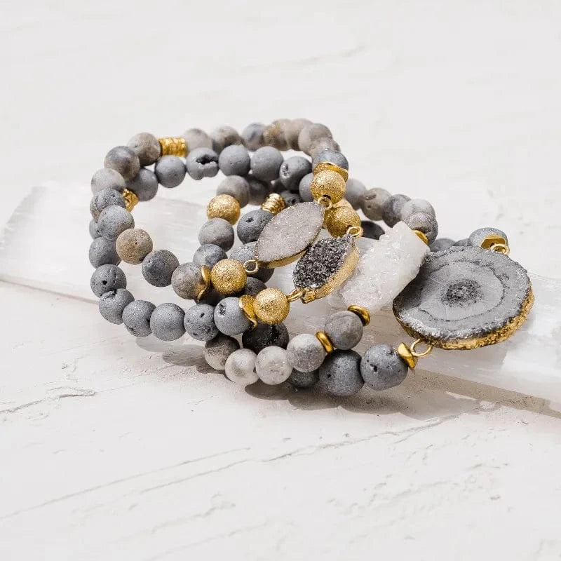 Set of gray and gold beaded bracelets on a light surface