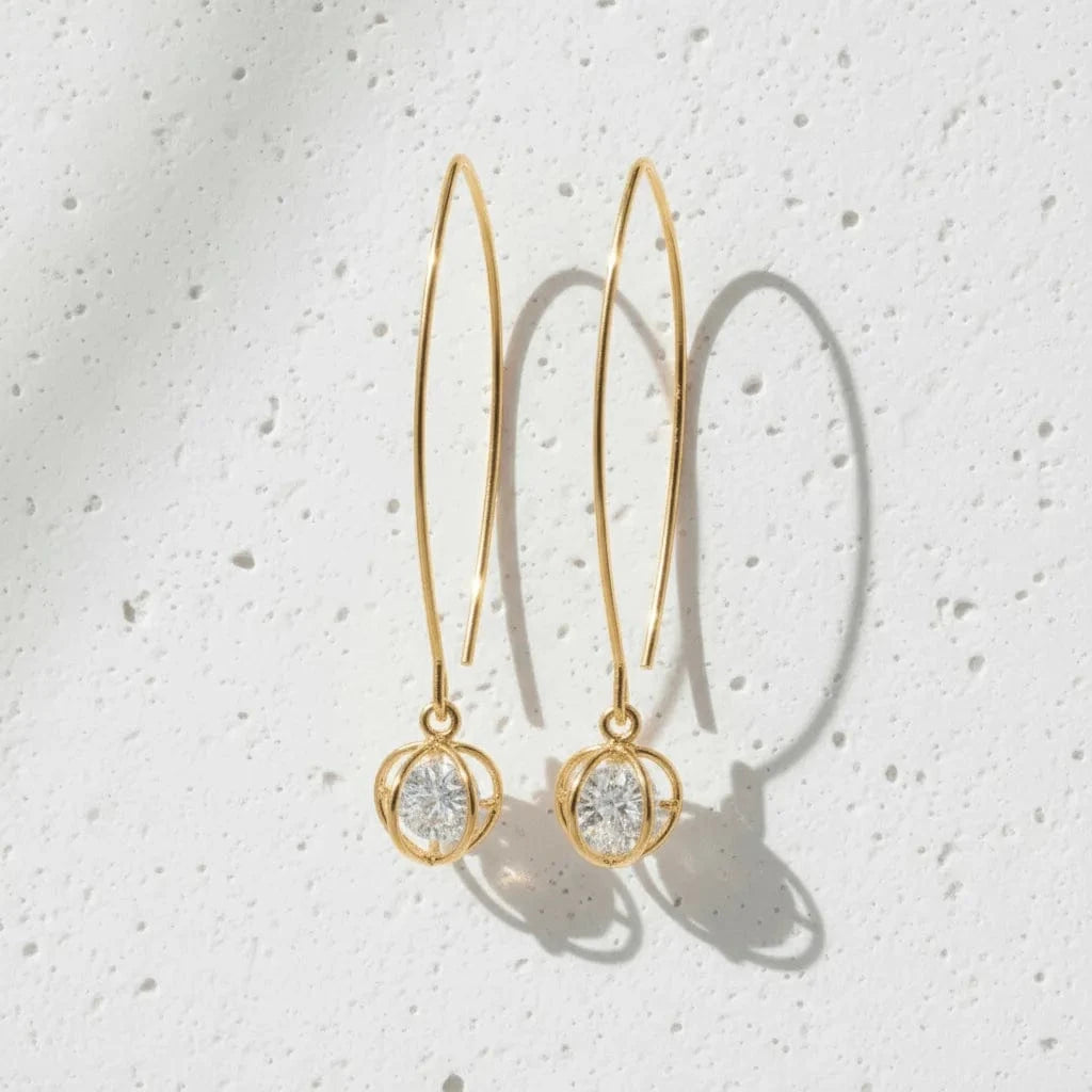 Gold hoop earrings with circular designs on a textured white background