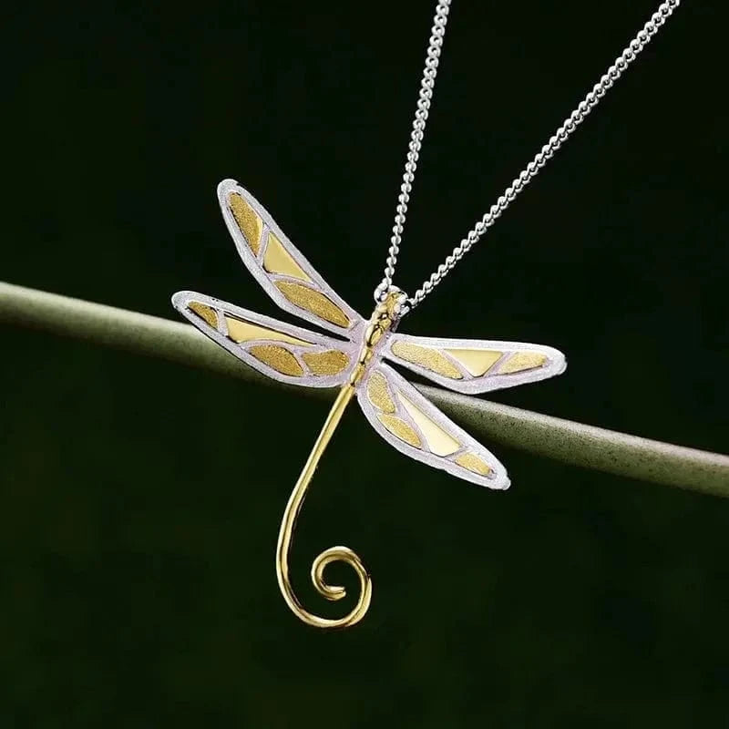 Dragonfly-shaped pendant on a chain against a dark background