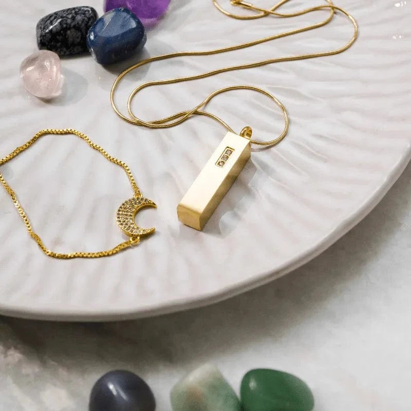 Gold necklaces with pendants on a white plate surrounded by stones