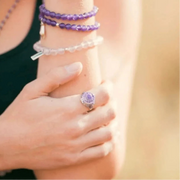 Close-up of a person wearing a purple ring and bracelets on a blurred background