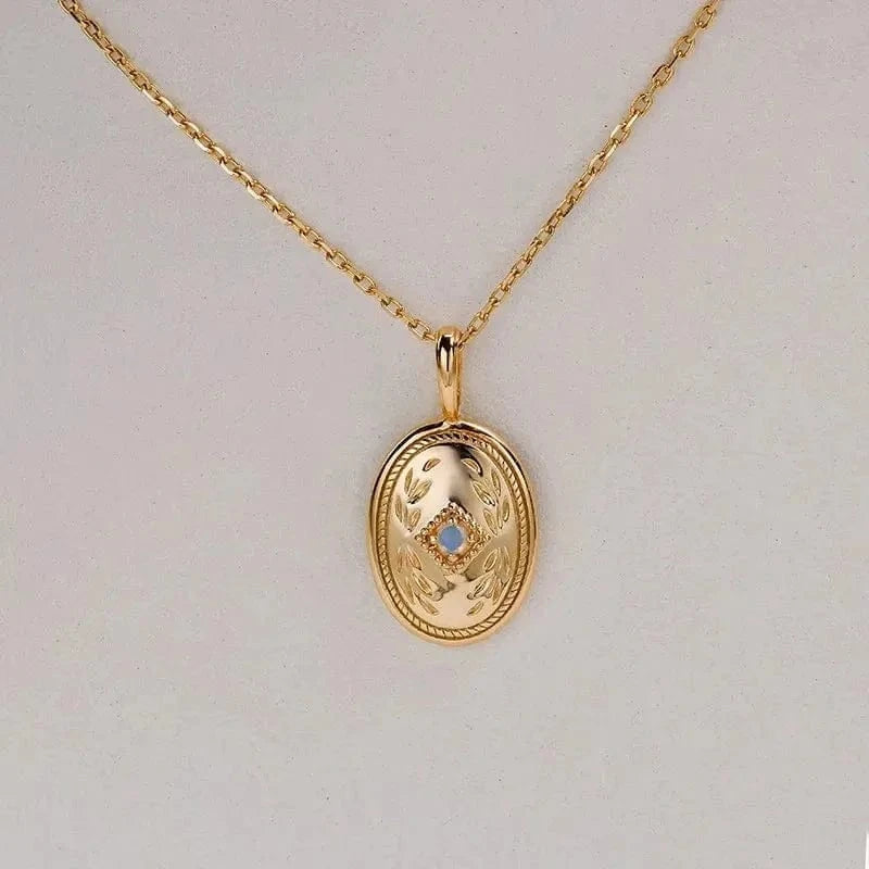 Gold necklace with an oval pendant on a light gray background