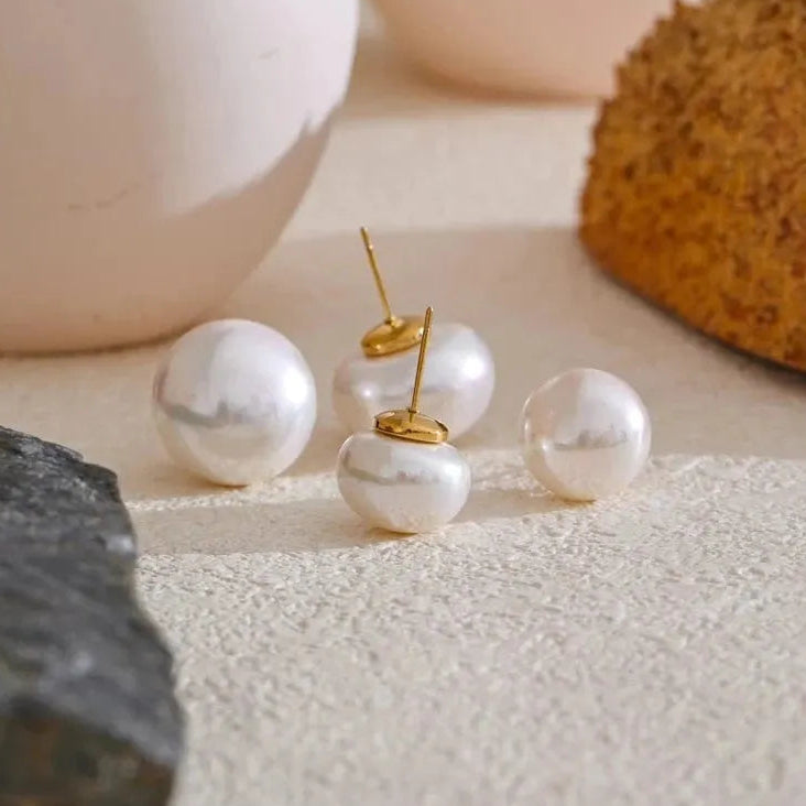 Pearl earrings with gold accents on a textured surface