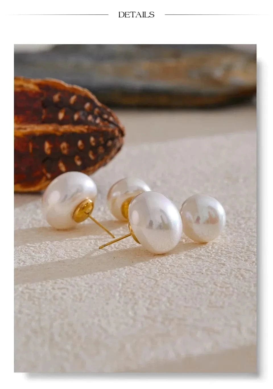 Pearl earrings on a textured surface with a blurred background