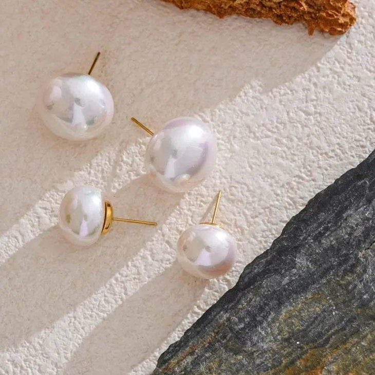 Pearl earrings on a textured surface with natural elements