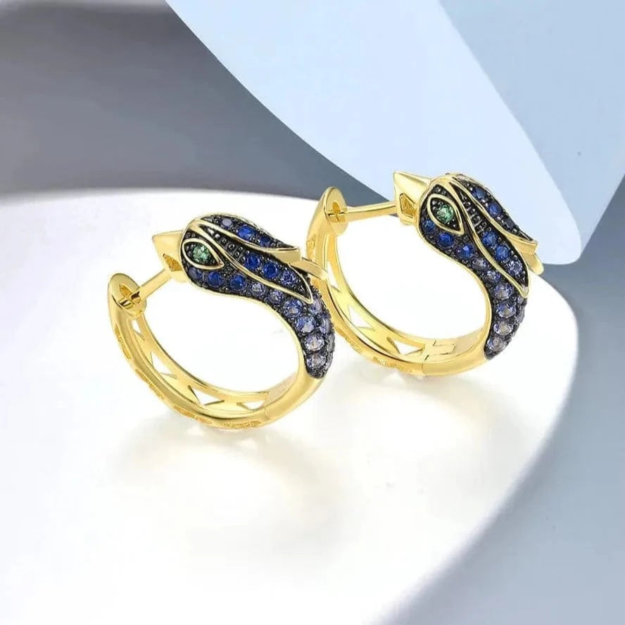 Gold hoop earrings with gemstones on a light background