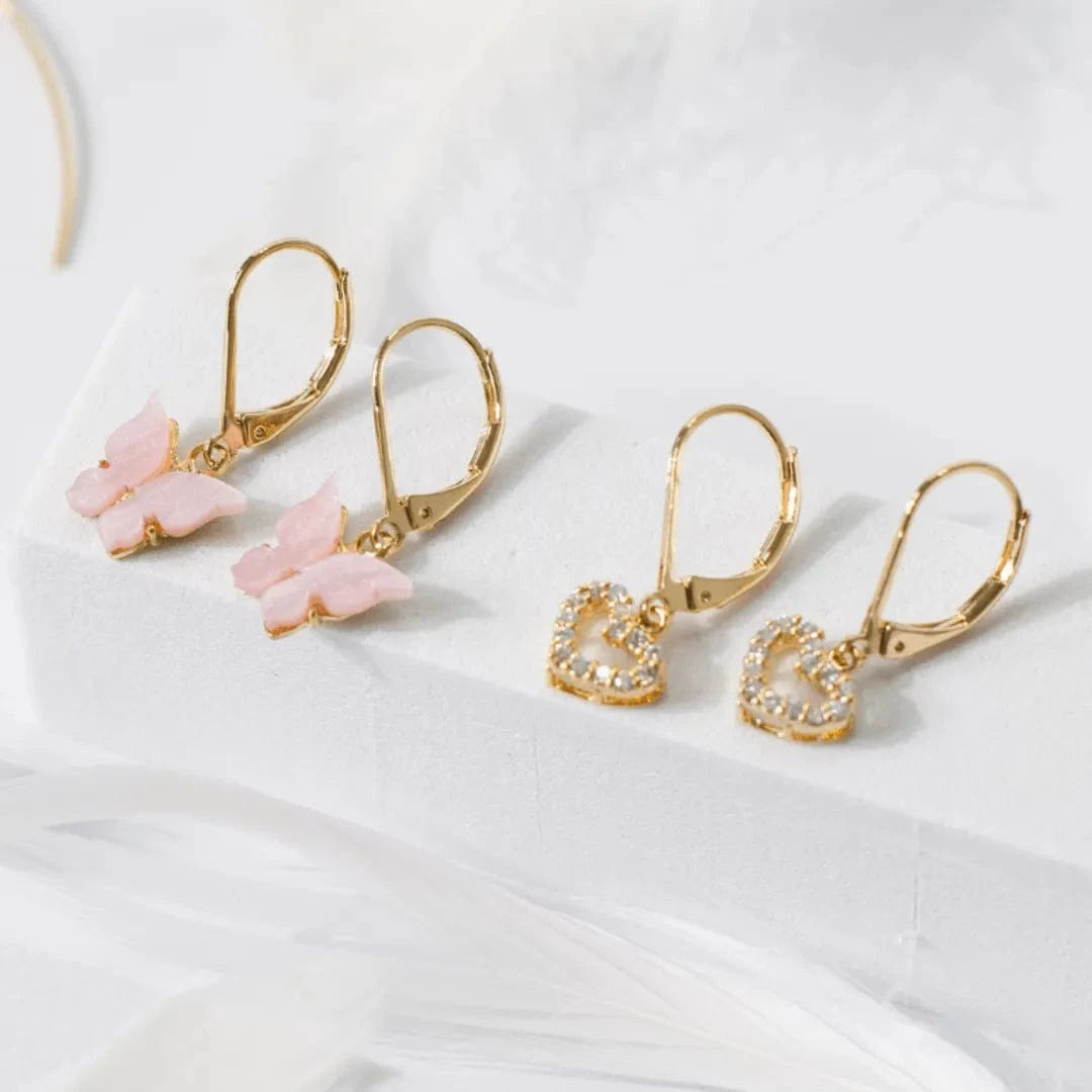 Gold earrings with pink butterfly charms on a white background
