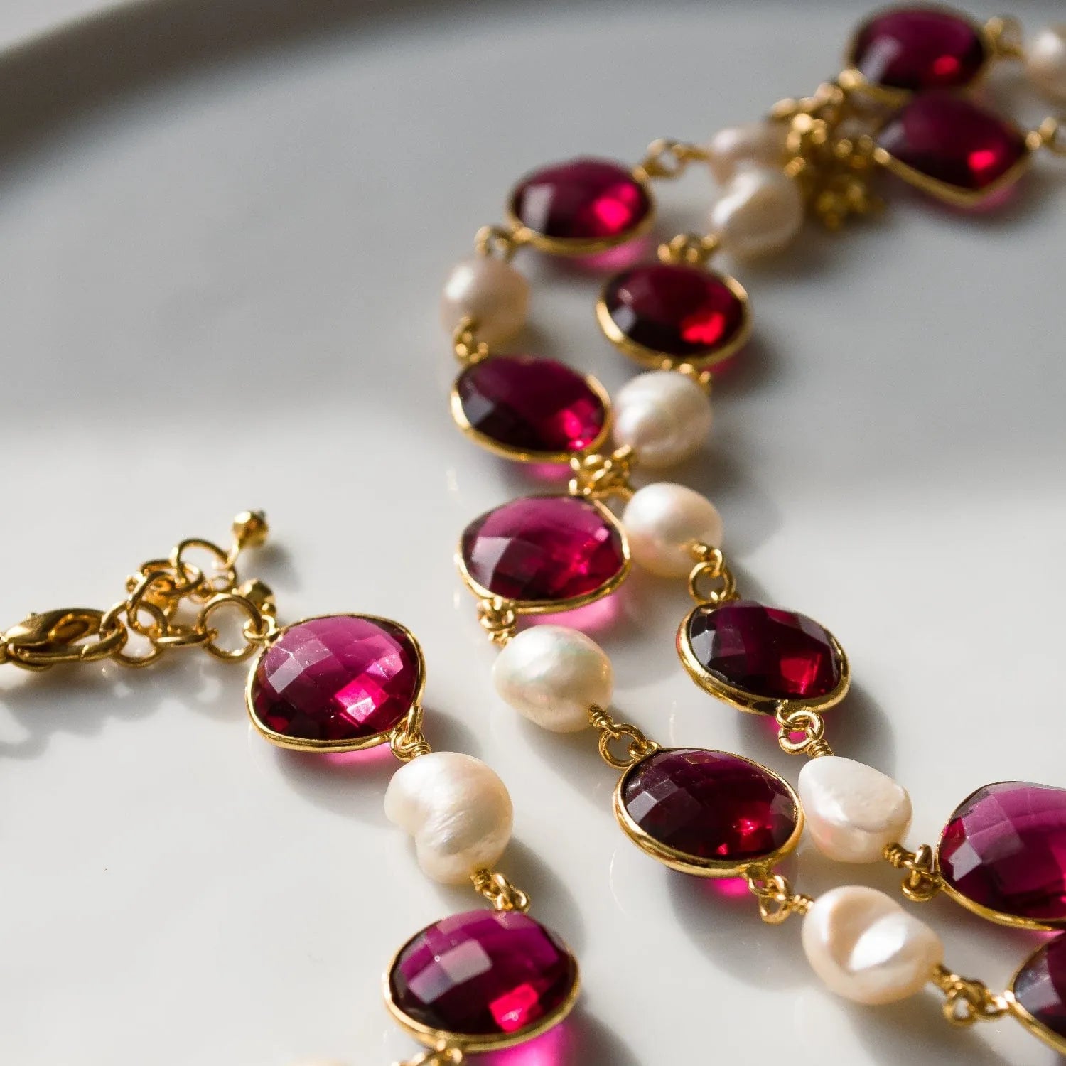 Necklace with red gemstones and pearls on a white surface