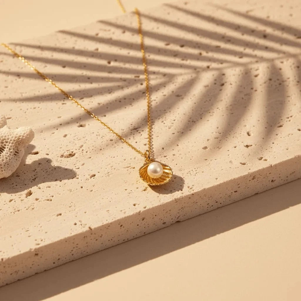 Gold necklace with a pearl pendant on a sandy surface