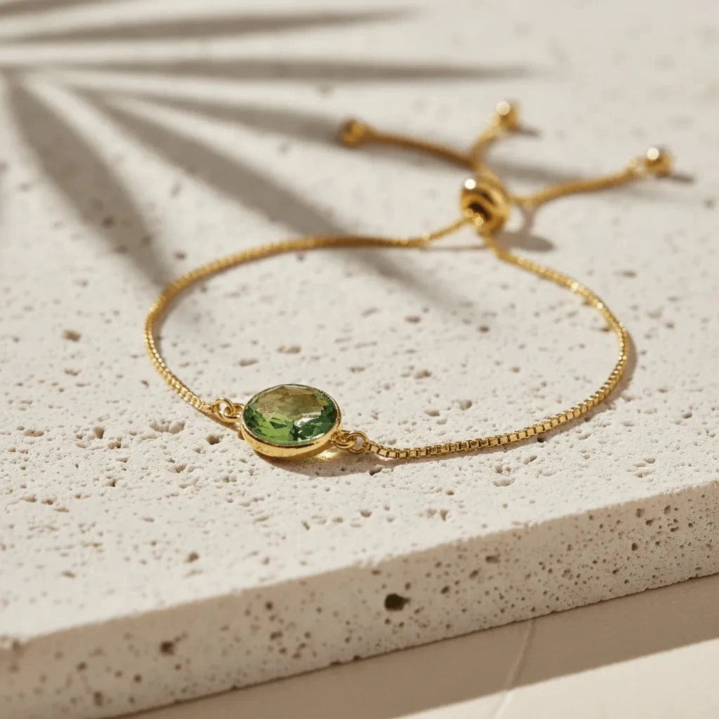 Gold bracelet with a green gemstone on a textured surface