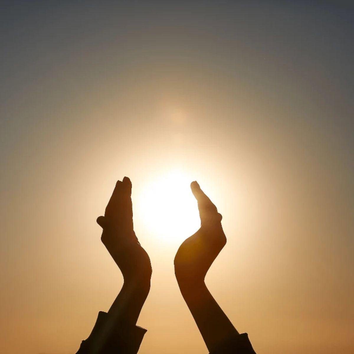 Hands holding a low setting sun — winter solstice rituals and intention setting for the longest night