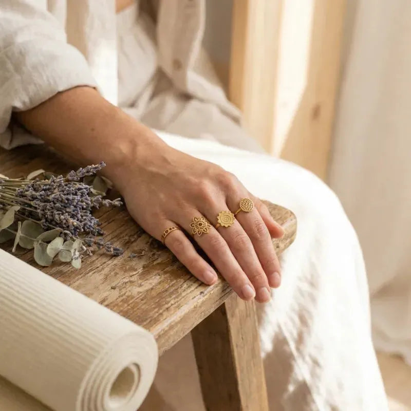 Hand with gold rings holding lavender on a wooden surface