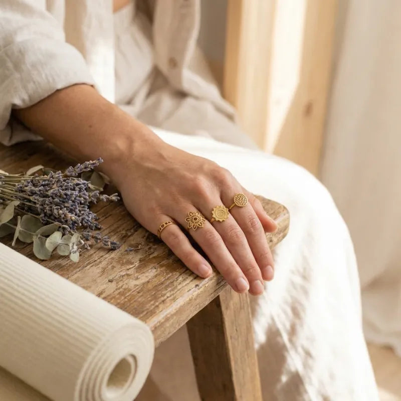 Hand with gold rings holding lavender on a wooden surface
