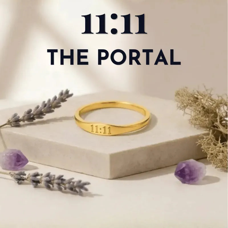 Gold ring with '11:11' engraving on a beige platform with lavender and amethyst stones, branded '11:11 The Portal'.
