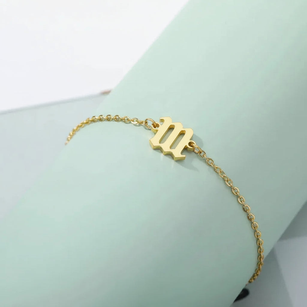 Gold bracelet with a unique design on a light green stand.
