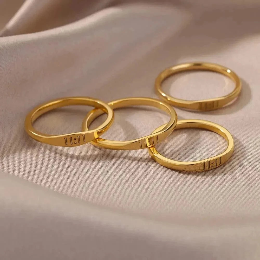Four gold rings stacked on a beige fabric background