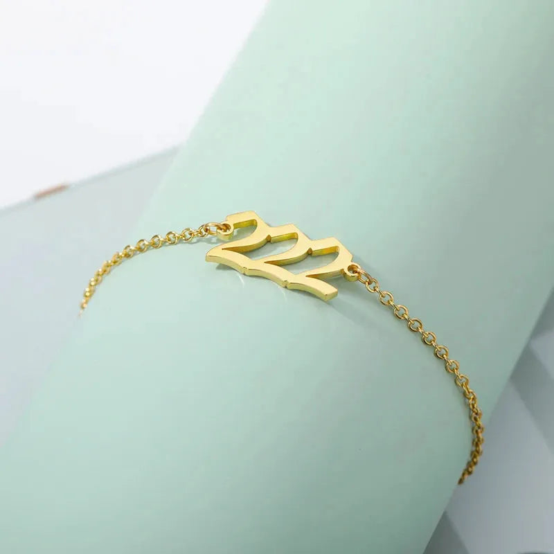 Gold bracelet with 222 charm on a light green background