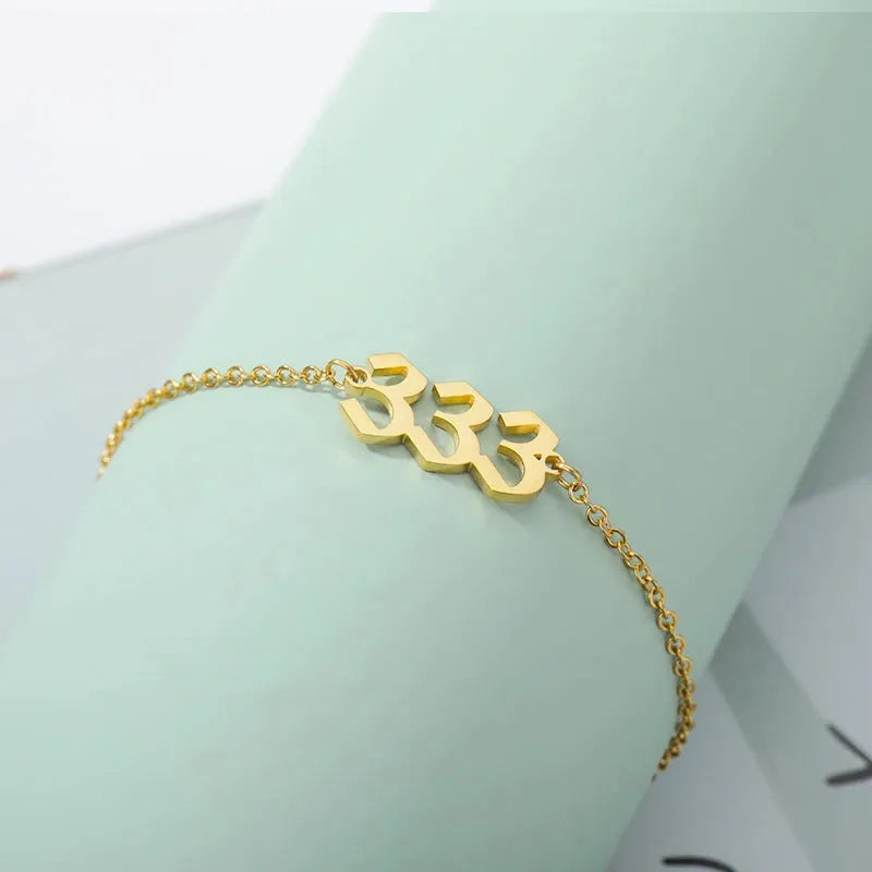 Gold bracelet with a unique 333 design on a light green background