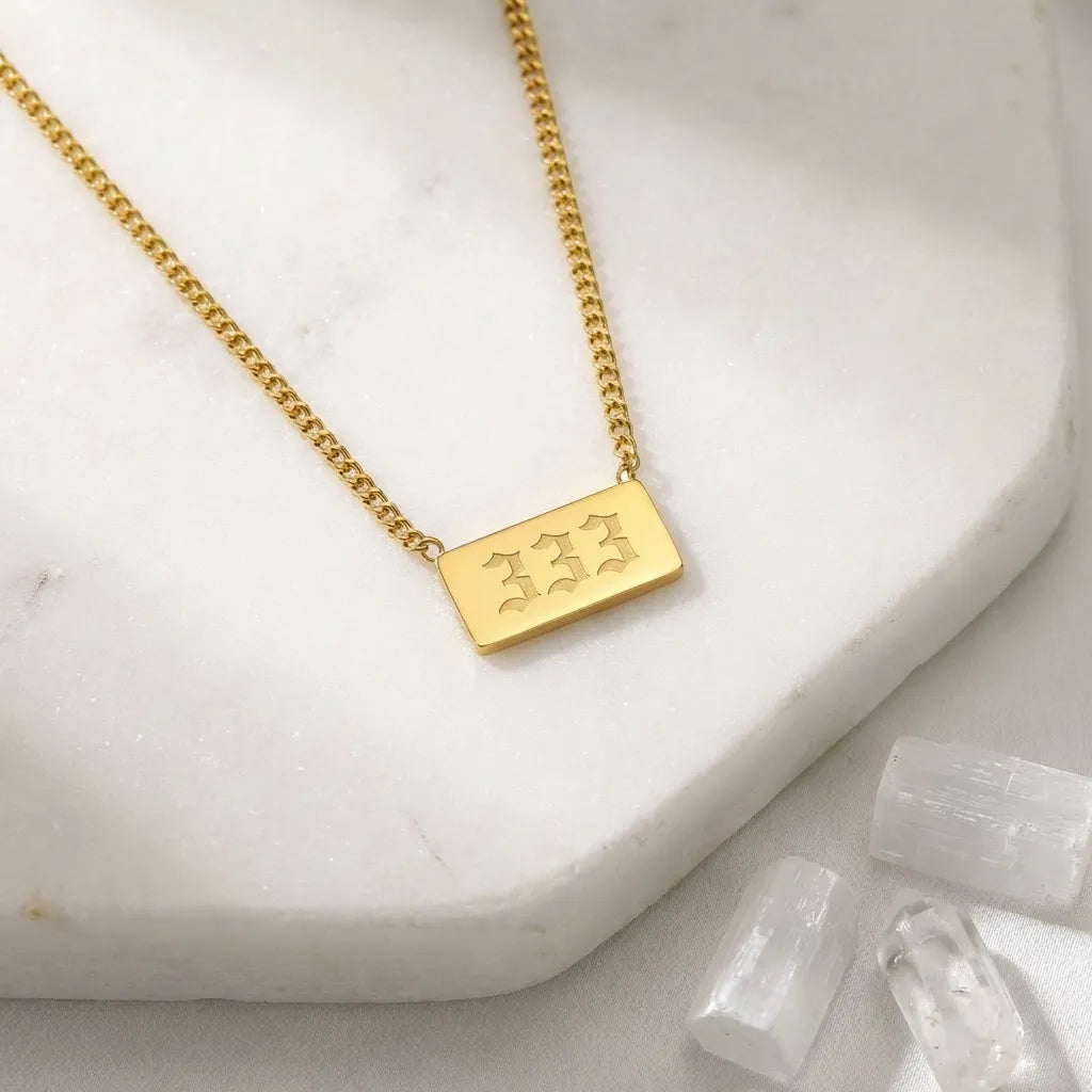 333 gold angel number rectangle pendant necklace with crystals on a light background