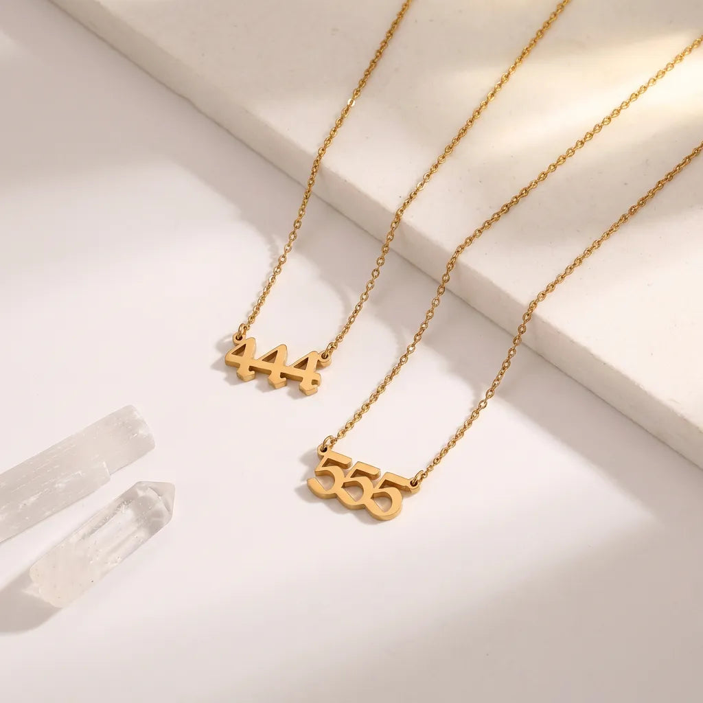 Two gold necklaces with unique numbers on a light background